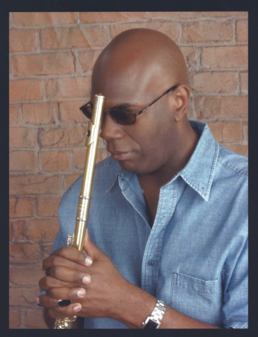 Black man with blue shirt holding flute