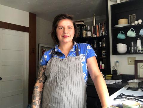 White woman wearing blue flowered shirt and gray apron