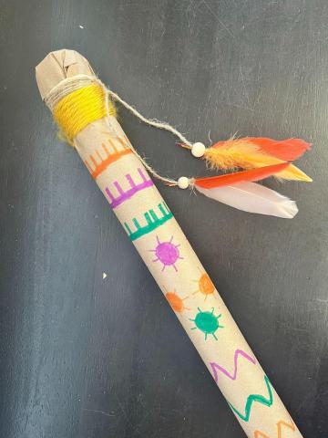 Rainstick decorated with markers and feathers hanging from end