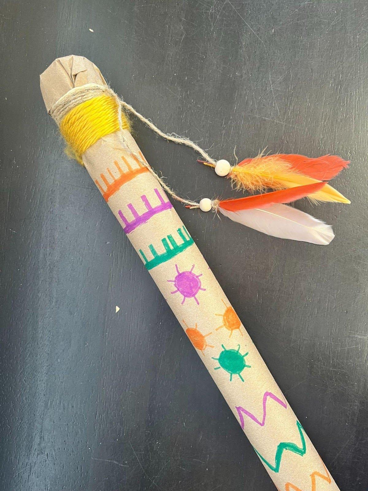 Rainstick decorated with markers and feathers hanging from end