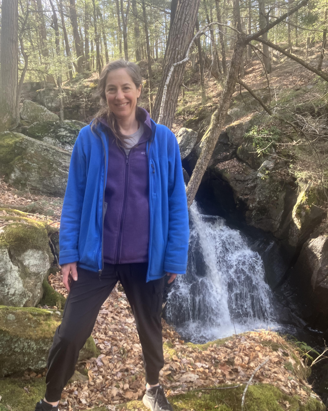  a picture of a woman standing beside a waterfall 