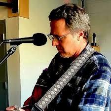 A photograph of Kent Besocke playing a banjo